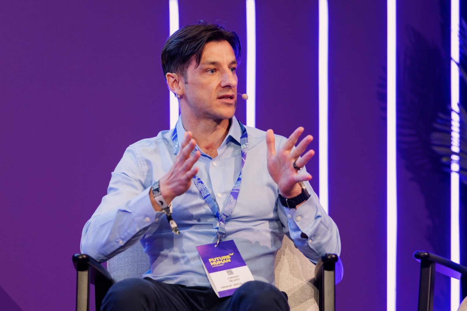 Delano gesturing while speaking on a panel stage in Dubai